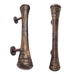 May include: A pair of ornate brass door pulls with intricate designs. The pulls are cylindrical with a rounded top and bottom. The designs are in a geometric pattern.
