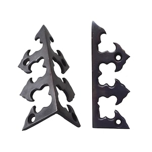 May include: Two dark metal corner brackets with an ornate, openwork design. One is L-shaped, and the other is a flat piece. Each has a series of curved cutouts and small holes, suggesting a decorative or architectural element.