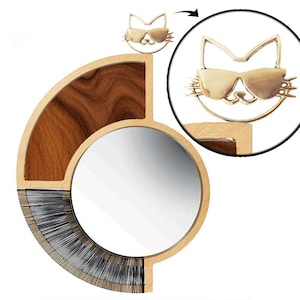 Puede incluir: Un espejo redondo con un marco de madera y un diseño en forma de gato. El marco es de madera con un acabado natural. El espejo está rodeado por un borde decorativo de rayas negras y blancas. El diseño del gato es de metal dorado y lleva gafas de sol.