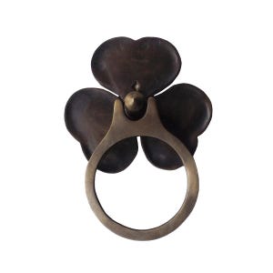 Może przedstawiać: Mosiężny uchwyt w kształcie koniczyny z ciemnobrązowym wykończeniem. Pierścień jest gładki i ma zaokrąglony brzeg.