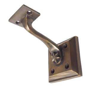 May include: A bronze-toned handrail bracket with a square base and mounting plate. The curved arm features a decorative starburst design. The bracket has a vintage aesthetic and is designed for wall mounting.