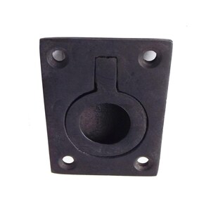 May include: A dark brown, rectangular flush pull with a circular handle and four screw holes. The handle is a ring shape that is recessed into the rectangular plate. The hardware is made of metal.
