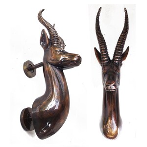 May include: A pair of antique bronze door handles shaped like an antelope head with long, curved horns. The handles are mounted on a round base.