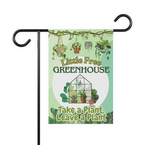 以下が含まれることがあります： 黒い金属製のスタンドが付いたガーデンフラッグ。旗は、"Little Free GREENHOUSE"と"Take a Plant, Leave a Plant"という言葉が入った薄緑色の背景が特徴です。デザインには、植物と温室のイラストが含まれています。