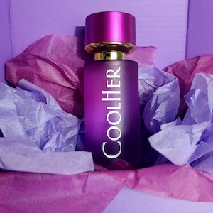 Op de afbeelding: Een paarse glazen fles parfum met een gouden dop en het woord "COOLHER" gedrukt op de voorkant.