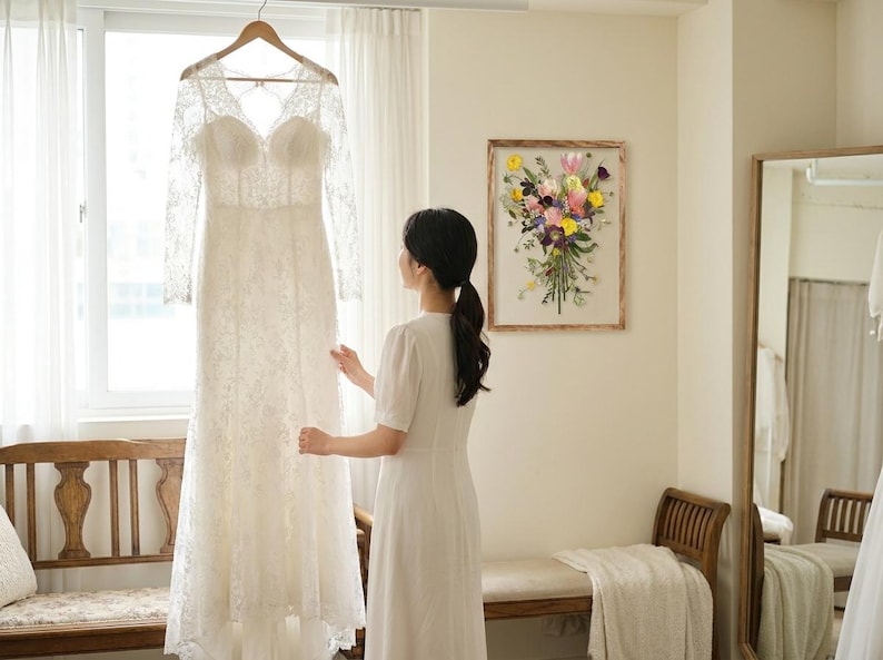 May include: A floor-length white lace wedding dress with long sleeves, a sweetheart neckline, and a sheer lace bodice. The dress features intricate floral embroidery throughout the fabric, a fitted waist, and a flowing skirt that reaches the floor.