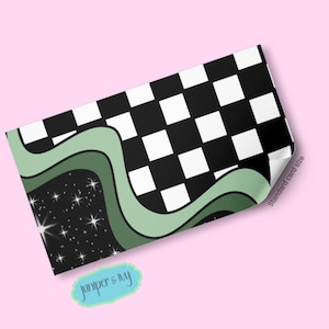 May include: A rectangular card with a black and white checkered pattern on the top right. The bottom left features a black space with white stars and a green wavy design. The card has the text "Juniper & Ivy" in a light blue oval.