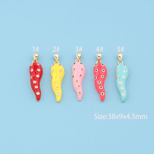 May include: Five colorful enameled charm pendants in red, yellow, pink, red, and turquoise. Each pendant is shaped like a chili pepper with white polka dots and a gold-tone bail. The size is 38x9x4.5mm.