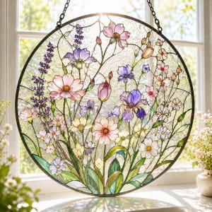 May include: A circular stained glass suncatcher featuring a vibrant floral arrangement with purple lavender, pink cosmos, blue irises, and yellow wildflowers. The piece is framed in a dark metal border and suspended by a black chain for hanging.