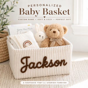 May include: A cream-colored corduroy storage basket featuring the name Jackson in dark brown script lettering. Inside the basket are a tan teddy bear with a bow, a white crocheted rabbit, a white cloth with a rainbow, and a book titled Guess How Much I Love You.