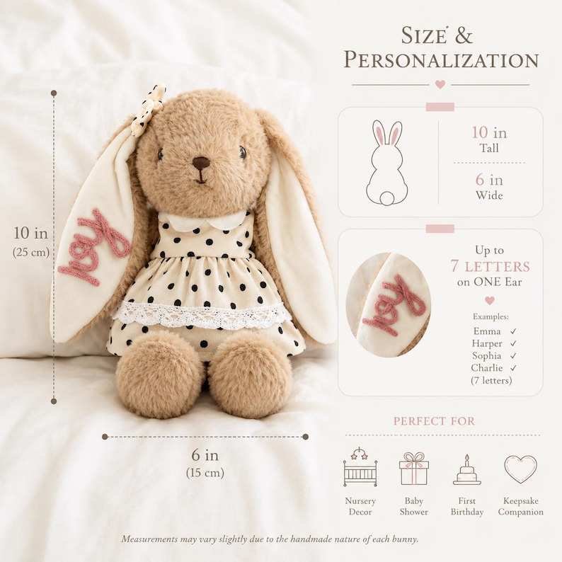 May include: A plush tan bunny with long ears, wearing a cream dress with black polka dots and white lace trim. The bunny measures 10 inches tall and 6 inches wide. One ear features the embroidered name Joy in pink script text.