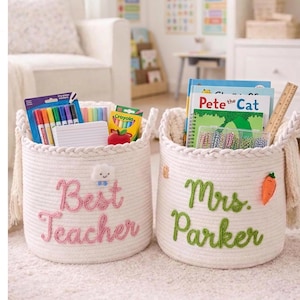 May include: Two off-white woven rope storage baskets with braided rims and side tassels. One basket features pink embroidered text reading Best Teacher with a cloud icon, while the other has green text reading Mrs. Parker and a carrot icon.