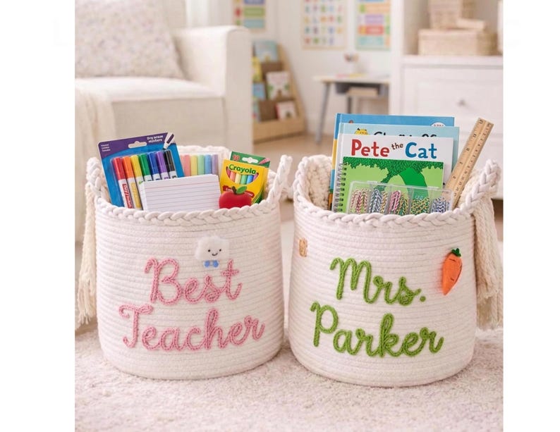 May include: Two off-white woven rope storage baskets with braided rims and side tassels. One basket features pink embroidered text reading Best Teacher with a cloud icon, while the other has green text reading Mrs. Parker and a carrot icon.