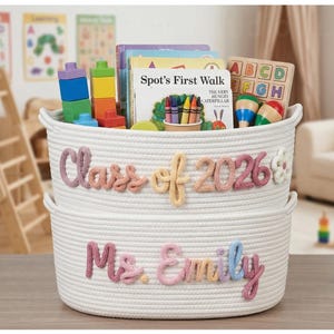 May include: Two stacked white woven rope baskets featuring pastel-coloured yarn lettering. The top basket displays the text Class of 2026 with a flower accent, while the bottom basket features the name Ms. Emily in cursive script lettering.