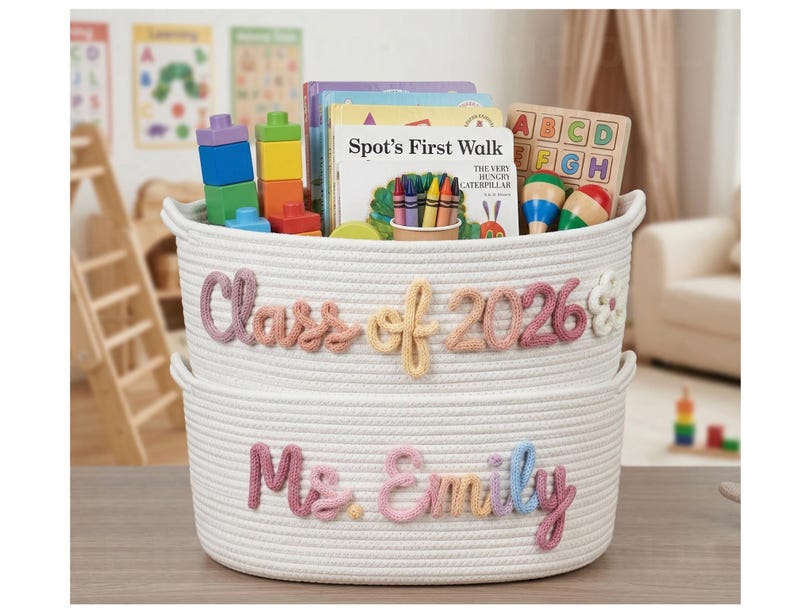 May include: Two stacked white woven rope baskets featuring pastel-coloured yarn lettering. The top basket displays the text Class of 2026 with a flower accent, while the bottom basket features the name Ms. Emily in cursive script lettering.