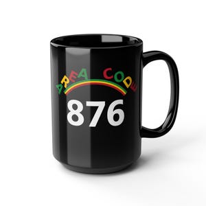 Könnte beinhalten: Ein glänzender schwarzer Keramikbecher mit dem Text AREA CODE in einer geschwungenen, mehrfarbigen Schrift über den großen weißen Zahlen 876. Das Design enthält eine dünne, bogenförmige, regenbogenfarbene Linie, die den Text von den Zahlen trennt.