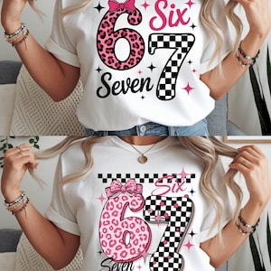 Könnte beinhalten: Weißes T-Shirt mit einer rosa Leopardenmuster-Nummer 6 und einer karierten Nummer 7. Das Wort "Six" ist in Rosa und "Seven" steht unter der Nummer 6. Das Design enthält rosa Sterne und eine rosa Schleife.