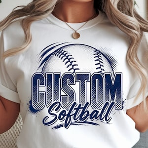 Op de afbeelding: Een wit T-shirt met korte mouwen en een donkerblauwe grafische print van een softbal met de tekst CUSTOM Softball. Het ontwerp bevat een halftoon-stippenpatroon en penseelstreekaccenten, gecentreerd op de borst van het kledingstuk.