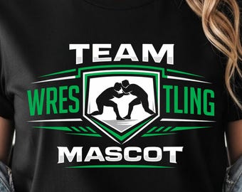 May include: Black t-shirt with a green and white graphic design. The design features the words "TEAM WRESTLING MASCOT" and a silhouette of two wrestlers in action. The shirt is made of a soft material.