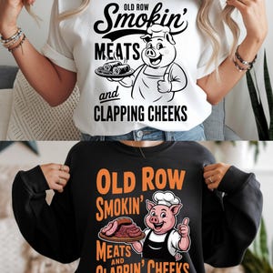 May include: Two shirts, one white and one black, each with a graphic. The white shirt features a cartoon pig chef holding a platter of food, with the text "Old Row Smokin' Meats and Clappin' Cheeks." The black shirt has the same design, but with orange text.