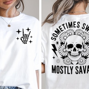Peut inclure: T-shirt blanc avec une main de squelette noire faisant le signe rock and roll et des étoiles sur le devant. Le dos du t-shirt présente un crâne entouré de fleurs, d'éclairs et le texte "SOMETIMES SWEET MOSTLY SAVAGE."