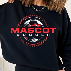 Peut inclure: Sweat-shirt noir avec un motif de ballon de football rouge et blanc. Le mot "MASCOT" est imprimé en rouge au-dessus de "SOCCER" en blanc. Le motif est entouré de lignes rouges, créant une esthétique sportive.