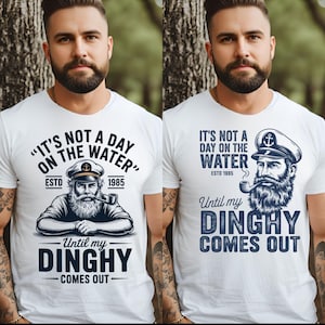 Peut inclure: T-shirts blancs avec un motif nautique. Les t-shirts présentent un marin avec une pipe et le texte "IT'S NOT A DAY ON THE WATER" et "Until my DINGHY COMES OUT". L'année "1985" est également incluse.