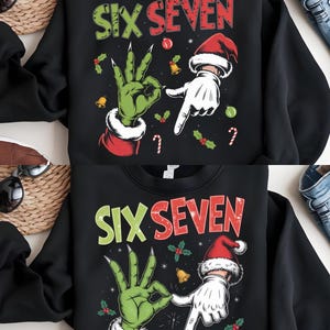 Peut inclure: Sweat-shirt noir avec l'inscription "SIX SEVEN" en vert et rouge. Le motif représente une main verte avec de longs ongles formant un signe "OK" et une main gantée pointant vers le bas. Des éléments de Noël, comme du houx, des cloches et des cannes en sucre, sont également présents.