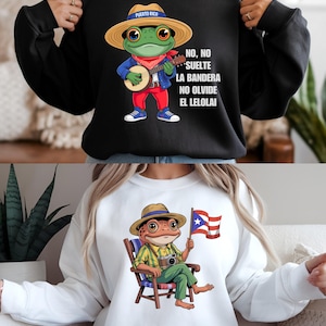 Puede incluir: Sudadera negra con una rana de dibujos animados con sombrero de paja y tocando el banjo. La rana viste pantalones rojos y una chaqueta azul. El texto en la camiseta dice "NO, NO SUELTE LA BANDERA NO OLVIDE EL LELOLAI".