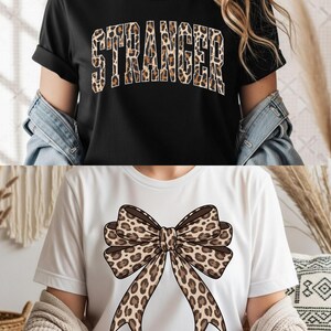 Peut inclure: Deux t-shirts. Le t-shirt du haut est noir avec le mot "STRANGER" dans un motif léopard. Le t-shirt du bas est blanc avec un grand motif de nœud léopard.
