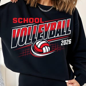 Puede incluir: Una sudadera negra de cuello redondo con un estampado gráfico que incluye el texto SCHOOL VOLLEYBALL 2026 en blanco y rojo. El diseño presenta un balón de voleibol rojo, blanco y negro estilizado con líneas de movimiento y una cuadrícula.