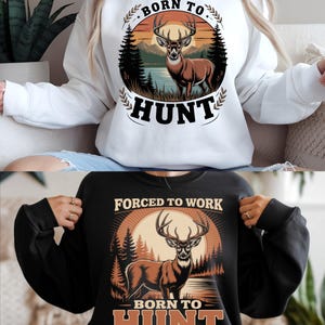 May include: White and black sweatshirts with a deer graphic. The deer is brown with large antlers, set against a sunset scene with trees and a lake. Text reads "BORN TO HUNT" and "FORCED TO WORK".