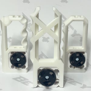 May include: Three white 3D-printed plastic handles with distinct geometric shapes and ergonomic finger grips. Each handle features a circular black mechanical component at the base with a central silver-colored metal fastener or magnetic insert.