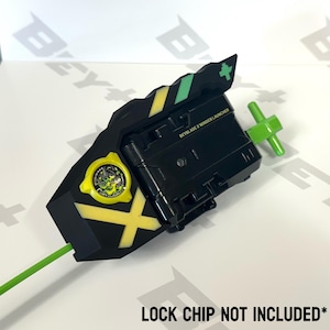 May include: Black and yellow Beyblade X Winder Launcher with a green pull cord and handle. The launcher has a circular emblem and the text "BEYBLADE X WINDER LAUNCHER". The text "LOCK CHIP NOT INCLUDED" is also visible.