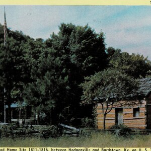 May include: Vintage postcard featuring Lincoln's Boyhood Home Site in Kentucky. The image shows a log cabin with a brick chimney, surrounded by lush green trees. A flagpole with an American flag stands nearby. The postcard has a yellow border and text at the bottom.