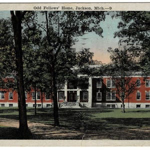 May include: Vintage postcard featuring the Odd Fellows' Home in Jackson, Michigan. The image shows a large brick building with multiple windows, framed by trees. The postcard has a sepia tone, with the text "Odd Fellows' Home, Jackson, Mich.-9" at the top.