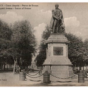 May include: Vintage black and white postcard featuring the Statue of Drouot in Nancy, France. The statue stands on a pedestal in a park setting, surrounded by trees. The postcard includes text: "61. - NANCY. - Cours Léopold - Statue de Drouot Leopold Avenue - Statue of Drouot."