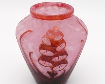 Peut inclure: Un vase en verre rose translucide avec un corps large et arrondi et une ouverture étroite. La surface présente un motif botanique gravé rouge-orangé plus foncé représentant une structure végétale segmentée avec des lignes courbes.