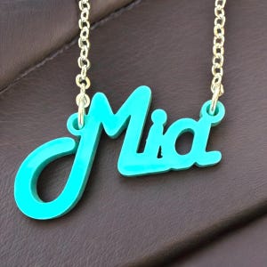 May include: A turquoise blue necklace with the name "Mia" spelled out in a cursive font.