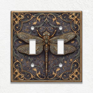 May include: Decorative double light switch cover featuring a detailed dragonfly design. The cover has a dark gray background with gold and green accents. The dragonfly is bronze-colored, and the design has an ornate, vintage aesthetic.