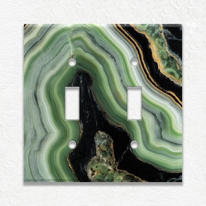 May include: A decorative double light switch cover with a green, black, and gold agate design. The cover features two light switch openings and four screw holes. The agate pattern has a layered, swirling appearance.