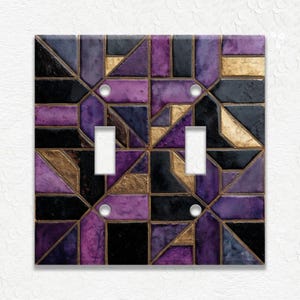 May include: A decorative double light switch cover with a geometric design. The cover features a mosaic pattern of black, gold, and shades of purple. The cover has two light switch openings and four silver screws.