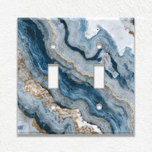 May include: A decorative double light switch cover with a blue, white, and gold agate design. The cover has two switch openings and four screw holes. The design features swirling patterns and gold accents.