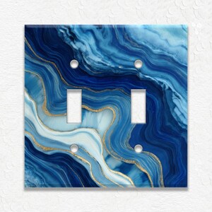 May include: A double light switch cover with a blue and white marbled design, accented with gold veins. The cover has two rectangular switch openings and two sets of screw holes. The design resembles agate stone.