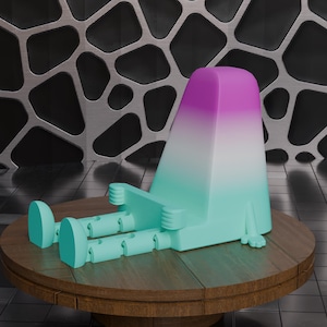 Puede incluir: Una escultura abstracta y caprichosa en tonos turquesa, blanco y morado. La figura está sentada sobre una mesa redonda de madera. La escultura tiene una cabeza alta y rectangular con un degradado de color y extremidades articuladas.