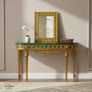 Könnte beinhalten: Eine goldfarbene Konsole mit einer grünen Marmorplatte und aufwendigen Details. Ein goldgerahmter Spiegel mit grünen Akzenten steht auf dem Tisch, zusammen mit zwei Büchern und einer weißen Vase mit Blumen. Der Tisch hat vier goldene Beine.