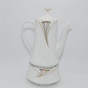 Op de afbeelding: Witte porseleinen koffiepot met deksel en voet. De pot heeft een gebogen handvat en tuit. Het is versierd met gouden en pastelkleurige abstracte ontwerpen. De pot is ontworpen met een unieke vorm.