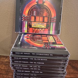 Könnte beinhalten: Ein Stapel CDs mit Musik aus den 50er Jahren. Auf der obersten CD-Hülle steht "THE '50s GENERATION" mit einer Jukebox-Grafik. Darunter befinden sich CDs aus der "YOUR HIT PARADE"-Reihe, darunter "THE UNFORGETTABLE '50s" und "THE '50s POP REVIVAL".