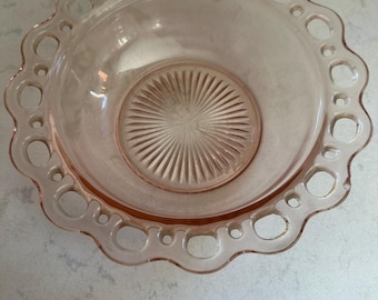 Pode incluir: Uma tigela de vidro rosa vintage com borda ondulada e padrão decorativo. A tigela apresenta uma série de recortes circulares ao redor da borda e um design texturizado em forma de estrela no centro. Perfeita para servir ou exibir.