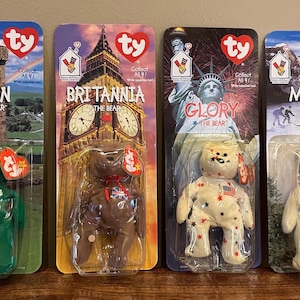 Puede incluir: Cuatro peluches Ty Beanie Baby en envases de plástico individuales. Los peluches son Erin el oso, Britannia el oso, Glory el oso y Maple el oso. Cada peluche lleva un atuendo diferente y tiene un fondo diferente.